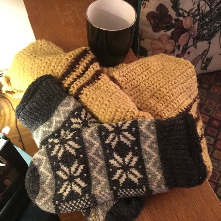 Scarf and mittens resting near a cup for coffee